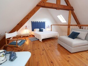 A cozy attic bedroom with a sloped ceiling, a bed, a sofa, a chair, and a small table. - Historic House in Normandy, Close to Beach (Réville)