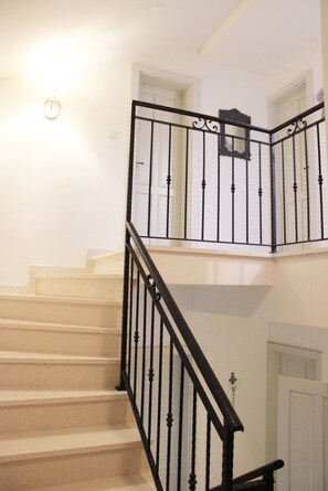 Eine Treppe mit schwarzem Metallgeländer und beigen Stufen.