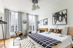 A modern bedroom with a large bed, a fireplace, and artwork on the walls. - Elegant 3BR Bastille Apartment (Paris)
