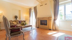 Tilava olohuone, jossa on takka, sohva ja suuri ikkuna, jossa on verhot.