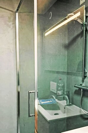 A glass-enclosed shower area with a visible sink and a handheld showerhead. - Beautiful apartment for 4 people with WIFI, TV and balcony (Leukerbad)