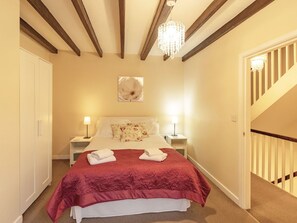 Une chambre à coucher avec un grand lit, deux tables de chevet, un lustre, un tableau et un escalier.