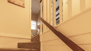 Eine Treppe mit Teppichstufen und einem hölzernen Geländer, die zu einem Raum mit Fenster und Tür führt.