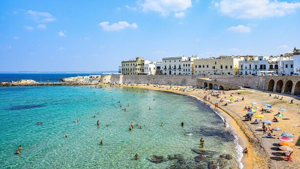 A coastal town with a clear beach, historic buildings, and a stone bridge. - Nice apartment for 8 guests with TV and balcony, close to Gallipoli (Baia Verde)