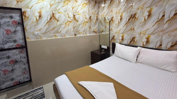 Habitación de hotel con una cama grande, una mesita de noche, un espejo y una pared con estampado floral.