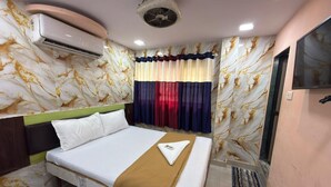 Habitación de hotel con cama, televisión, aire acondicionado y cortina con diseño de mármol.