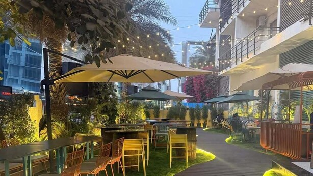 Een buitenterras met tafels, stoelen, parasols en een houten terras.