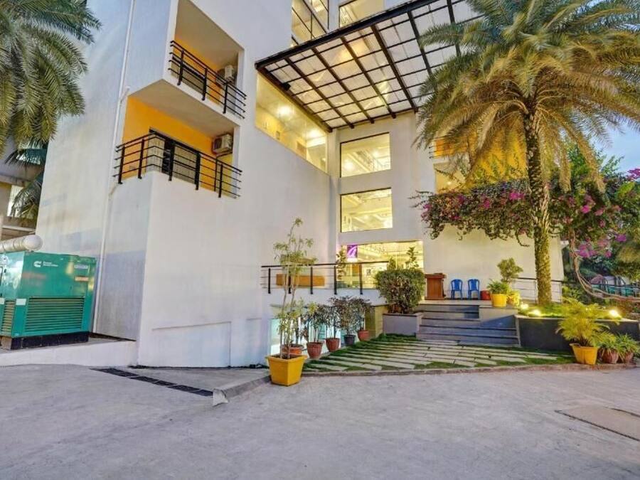 A modern building with a central staircase, multiple balconies, and potted plants.