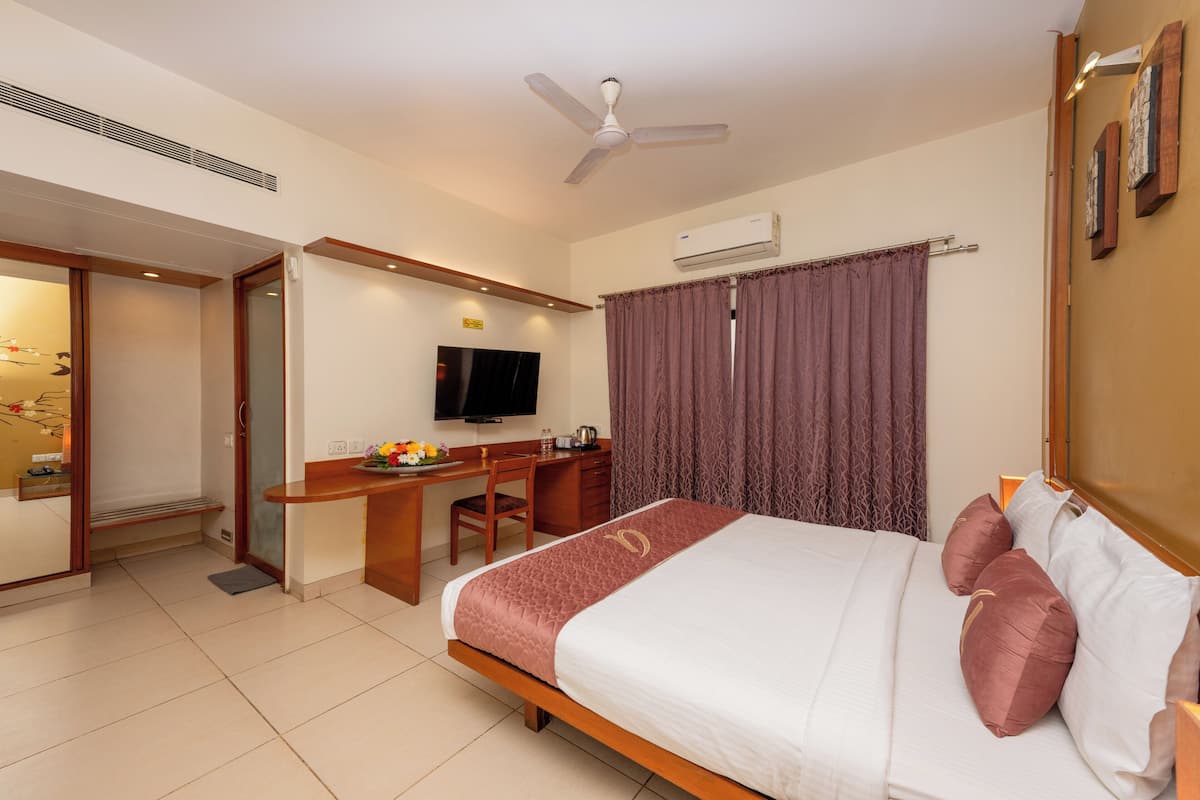 Ein Hotelzimmer mit Bett, Schreibtisch, Stuhl, Fernseher und Klimaanlage.