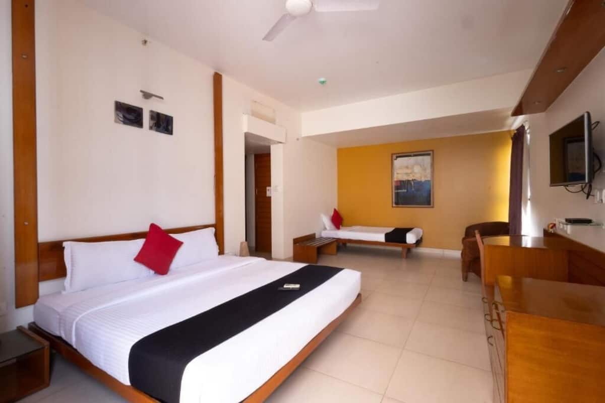 Ein Hotelzimmer mit einem großen Bett, einem kleineren Bett, einem Schreibtisch und einem Sessel.
