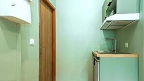 A compact kitchen with a wooden door, a sink, and a small countertop. - Bright, air-conditioned studio for 2 people (Paris)