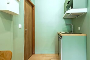 A compact kitchen with a wooden door, a sink, and a small countertop. - Bright, air-conditioned studio for 2 people (Paris)