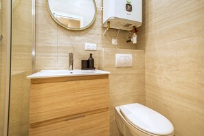 Ein Badezimmer mit Toilette, Waschbecken mit Spiegel und Dusche.