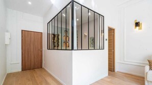 Ein Zimmer mit Holztür, Glastrennwand und weißer Wand mit einer Leuchte.