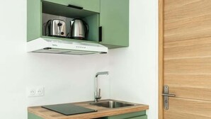 Eine kompakte Küche mit eingebautem Geschirrspüler, einer Edelstahl-Spüle und einer Holz Arbeitsplatte.