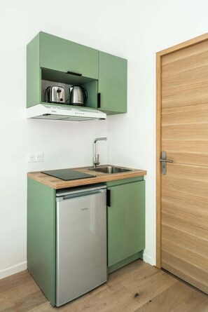 A compact kitchen with a built-in dishwasher, a stainless steel sink, and a wooden countertop. - Elegant 2-room air-conditioned apartment - Paris 17 (Paris)