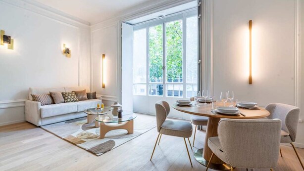 Ein modernes Wohnzimmer mit Sofa, Couchtisch und Essbereich mit Stühlen und Esstisch, gedeckt für ein Essen.