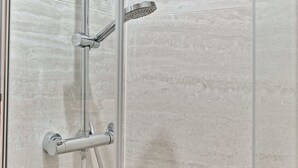 A shower enclosure with a handheld showerhead, a wall-mounted showerhead, and a handheld shower hose. - Studio climatisé, calme & tout équipé – Paris 17 (Paris)