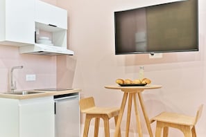 Eine Küchenzeile mit Backofen, Spüle und einer kleinen Essecke mit zwei Stühlen und einem Tisch.