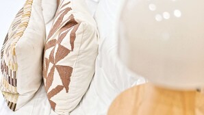 A bed with white bedding and patterned pillows. - Studio climatisé, calme & tout équipé – Paris 17 (Paris)