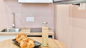 A kitchen with a round wooden table, a bottle of water, and croissants on a plate. - Studio climatisé, calme & tout équipé – Paris 17 (Paris)