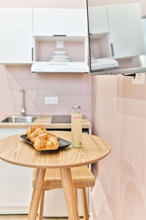 Eine Küche mit einem runden Holztisch, einer Wasserflasche und Croissants auf einem Teller.