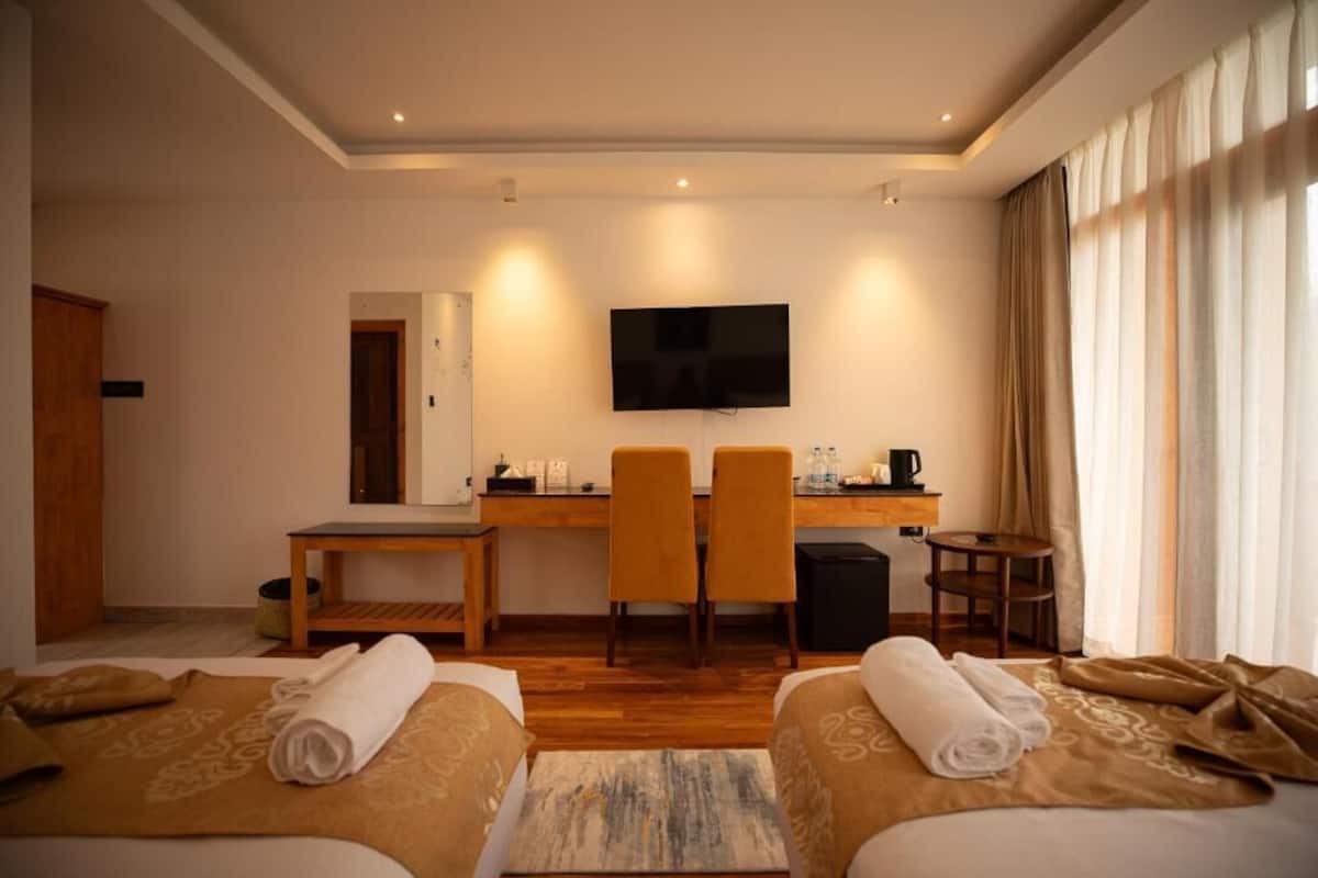 Une chambre d’hôtel avec deux lits, un bureau avec des chaises, une télévision et une machine à café.