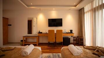 Habitación de hotel con dos camas, un escritorio con sillas, un televisor y una cafetera.