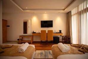 A hotel room with two beds, a desk with chairs, a television, and a coffee machine. - Nangter Retreat (Paro)