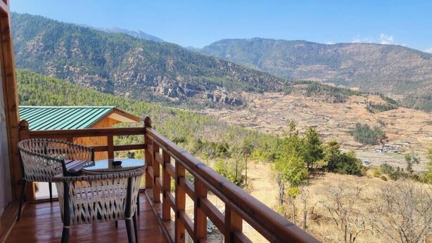 A wooden deck with a table and chairs overlooking a mountainous landscape. - Nangter Retreat (Paro)