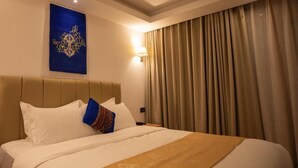 A hotel room with a large bed, beige curtains, and a wall-mounted lamp. - Nangter Retreat (Paro)