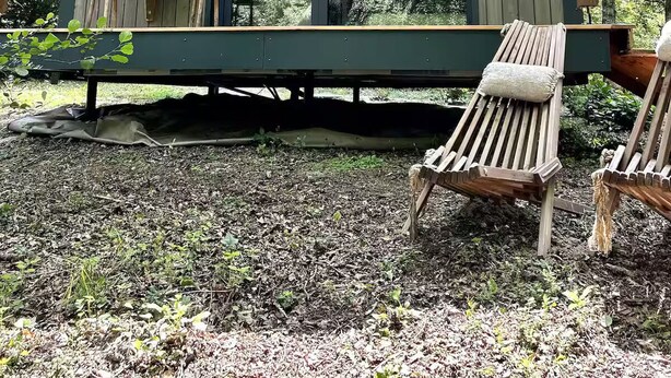 Une cabane en bois avec une véranda, un banc et une table.