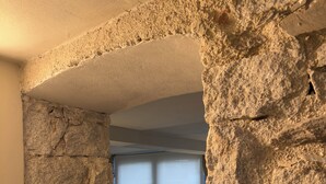 A stone archway leading to a living area with a black sofa and a large window. - Lake Orta elegant apartment. Vacation Lake Friends (Alzo)