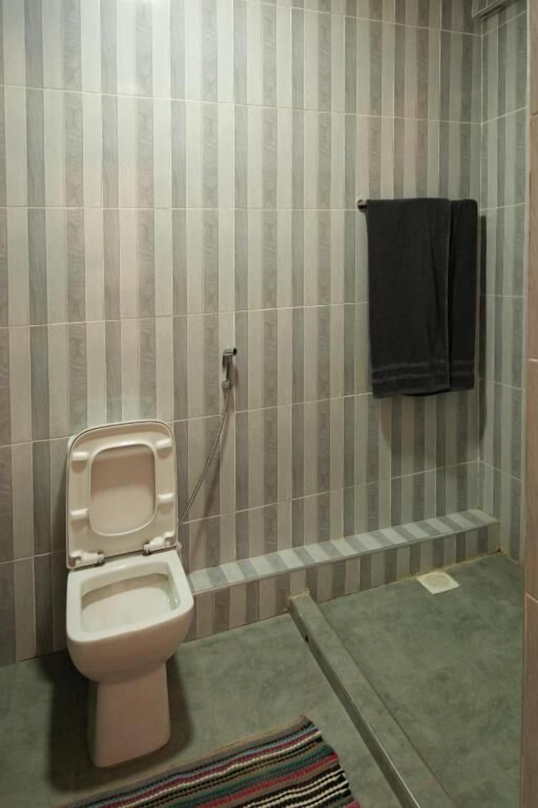 A bathroom with a toilet, a towel rack, and a shower area.