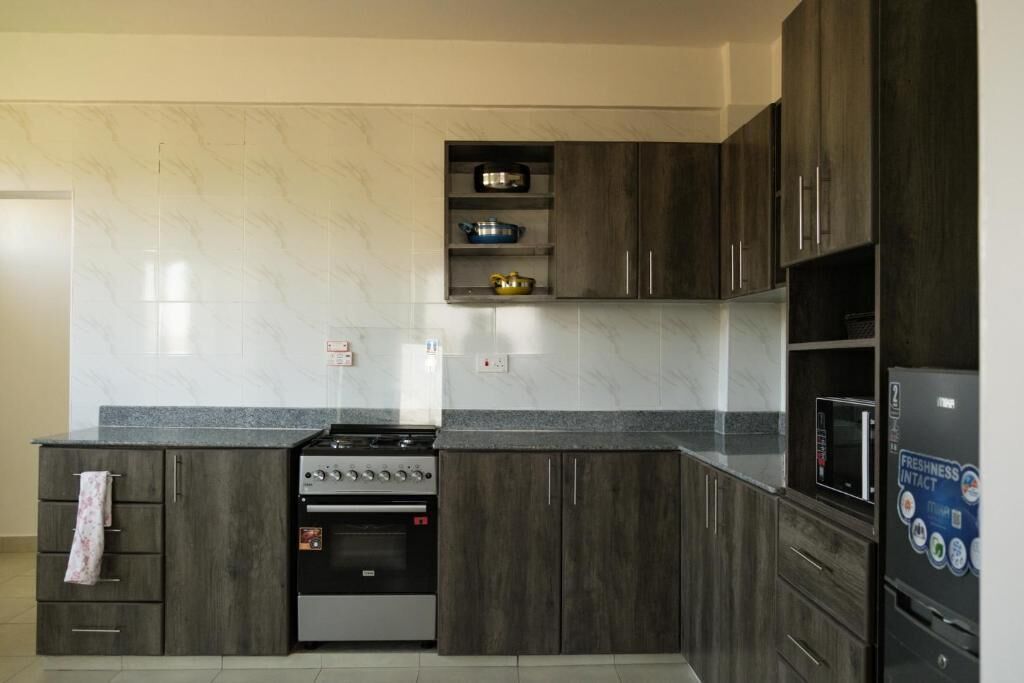 Una cocina moderna con armarios de madera oscura, horno empotrado y refrigerador de acero inoxidable.