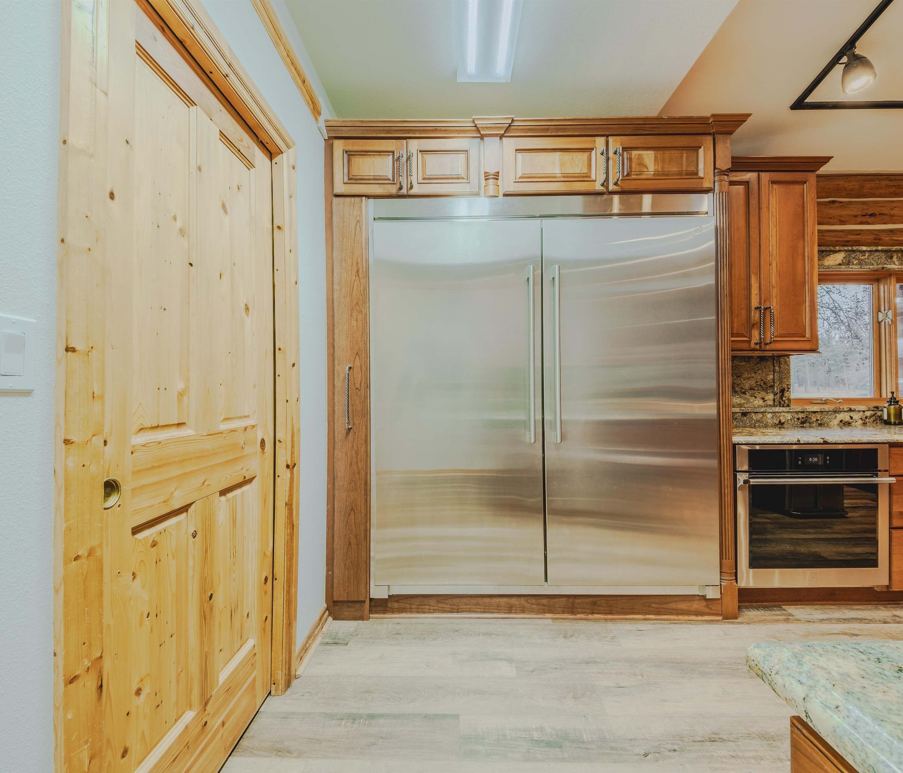 Une cuisine avec des meubles en bois, un réfrigérateur en acier inoxydable et un four encastré.