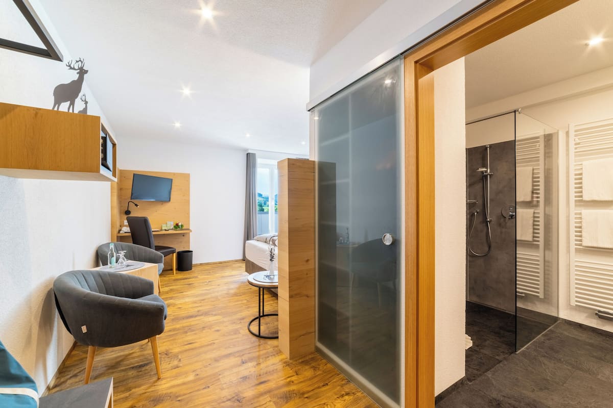 Ein modernes Interieur mit Holzboden, einer Glastrennwand, einer Duschkabine und einer Sitzecke mit Tisch und Stühlen.