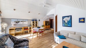 Uma sala de estar espaçosa com uma mesa de jantar, um sofá e um ventilador de teto.