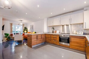 A modern kitchen with wooden cabinets, stainless steel appliances, and a central island. - 3BDR Terracotta House | Free Parking and Garden (Stoke-on-Trent)