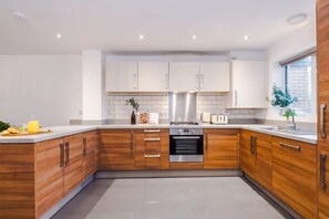 A modern kitchen with wooden cabinets, a stainless steel range, and a built-in oven.