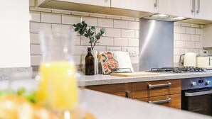 A kitchen with white tiled backsplash, stainless steel range hood, and a gas stove. - 3BDR Terracotta House | Free Parking and Garden (Stoke-on-Trent)