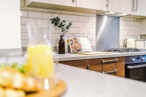 A kitchen with white tiled backsplash, stainless steel range hood, and a gas stove.