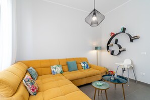 A modern living room with a sectional sofa, a round wall shelf, a white chair, and a small table. - Villa 'Falaride' with Private Pool, Wi-Fi, and Air Conditioning (Avola)