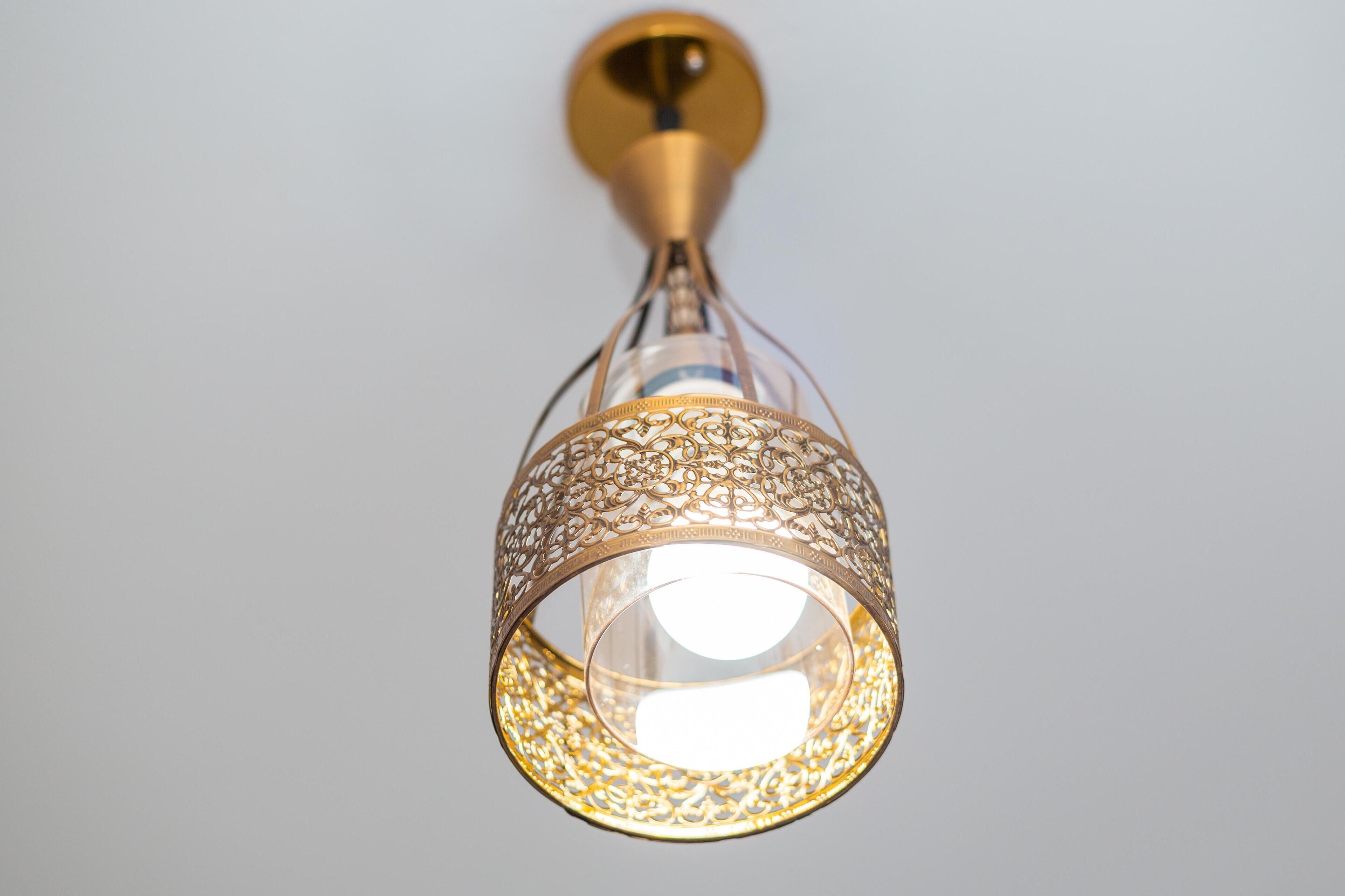 Un luminaire suspendu doté d’un abat-jour décoratif en verre et d’un socle en laiton.