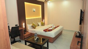 Una habitación de hotel con cama, escritorio, silla, mesa de centro y televisión.