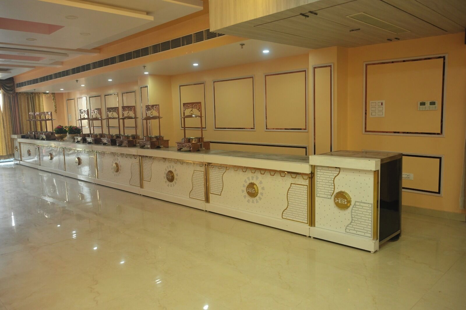 A long reception desk with decorative panels and a polished floor.