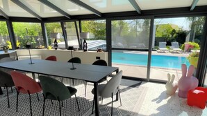 Une terrasse extérieure moderne avec une piscine, une table et des chaises, et une structure vitrée.