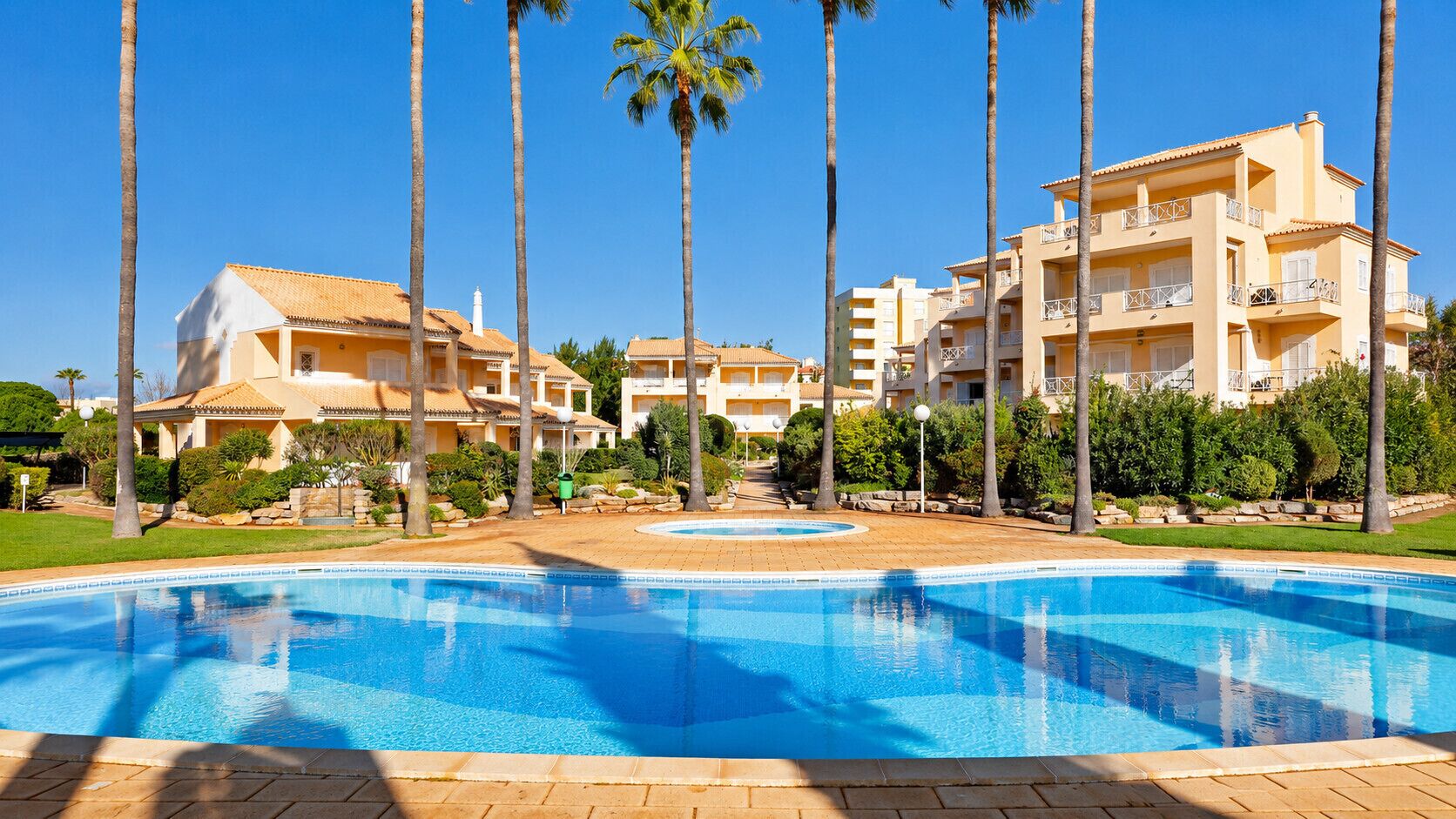 Ein Resort mit Schwimmbad, Palmen und mehrstöckigen Gebäuden.
