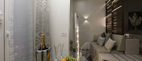 A modern living room with a glass table, a sofa, and a decorative wall.