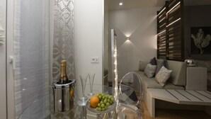 A modern living room with a glass table, a sofa, and a decorative wall. - Gian Giacomo Mora, 13 - Refined studio apartment downtown (Milan)